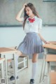 A woman in a school uniform standing in front of a classroom.