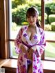 A woman in a kimono posing in front of a window.