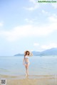 A woman in a blue bikini standing on a beach.