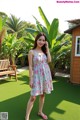 A woman standing in front of a green lawn.