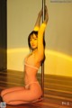 A woman in a pink lingerie sitting on a pole.