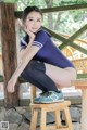 A woman sitting on top of a wooden stool.