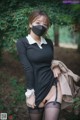 A woman wearing a black dress and a face mask.