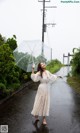 A woman in a white dress holding an umbrella in the rain.