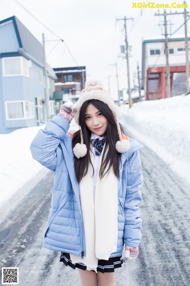 A woman in a blue jacket is standing in the snow.
