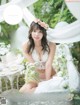 A woman in a white lingerie sitting on a chair with flowers in her hair.