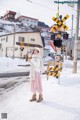 A woman standing in the snow next to a railroad crossing.