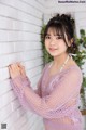 A young woman leaning against a white brick wall.