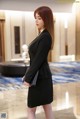 A woman in a black suit standing in a lobby.