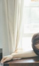 A woman leaning on a window sill with her head on the window sill.