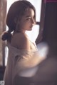 A woman in a white dress looking out a window.