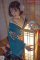 A woman in a blue kimono holding a lantern.