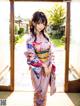 A woman in a kimono standing in front of a door.