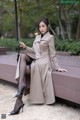 A woman sitting on a bench holding an umbrella.