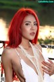 A woman with red hair wearing a white dress and pearls.