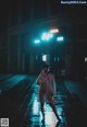 A woman wearing a face mask walking down a street at night.